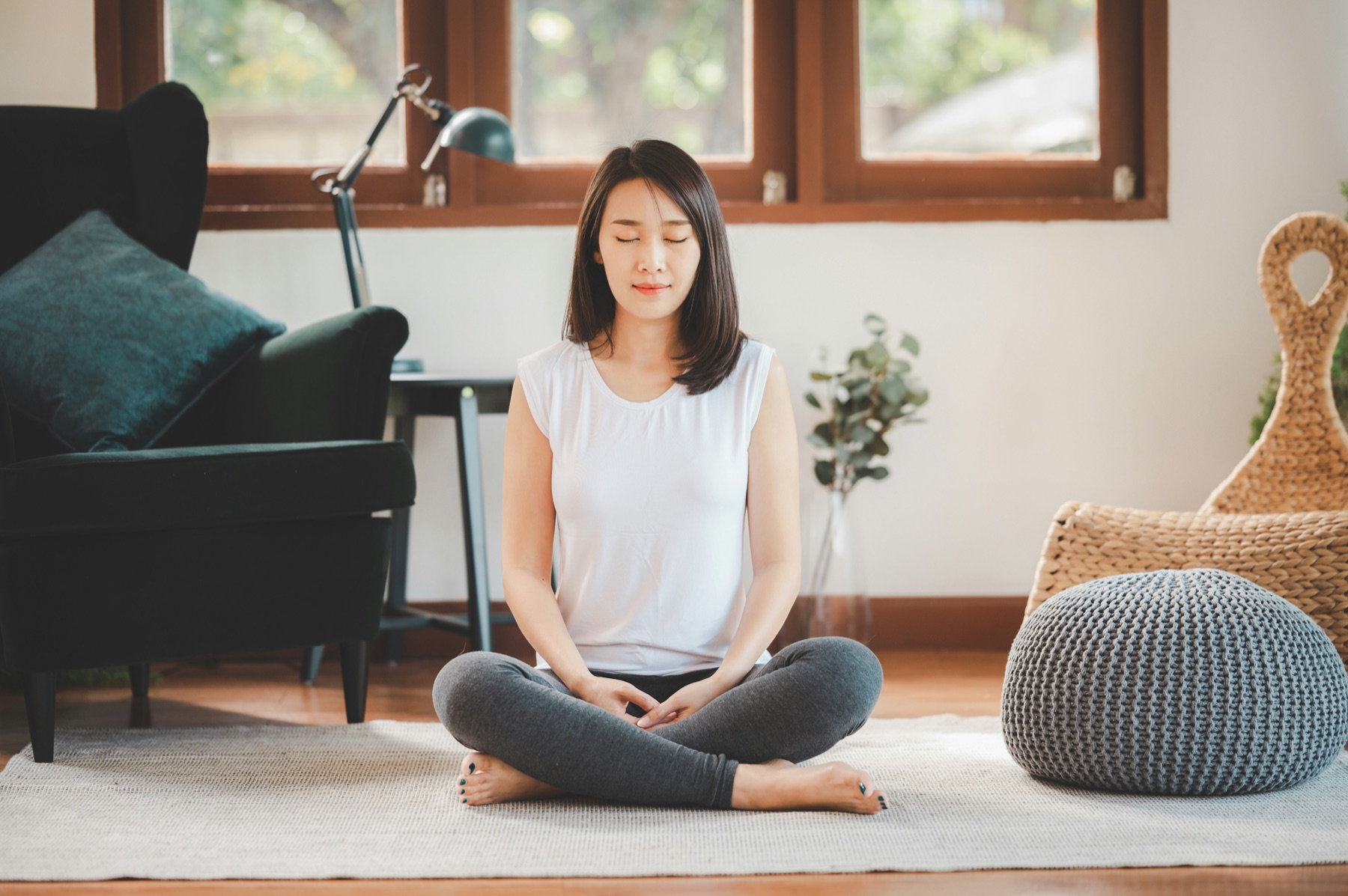 woman sitting cross-legged with eyes closed in a relaxed posture for a breathing exercise