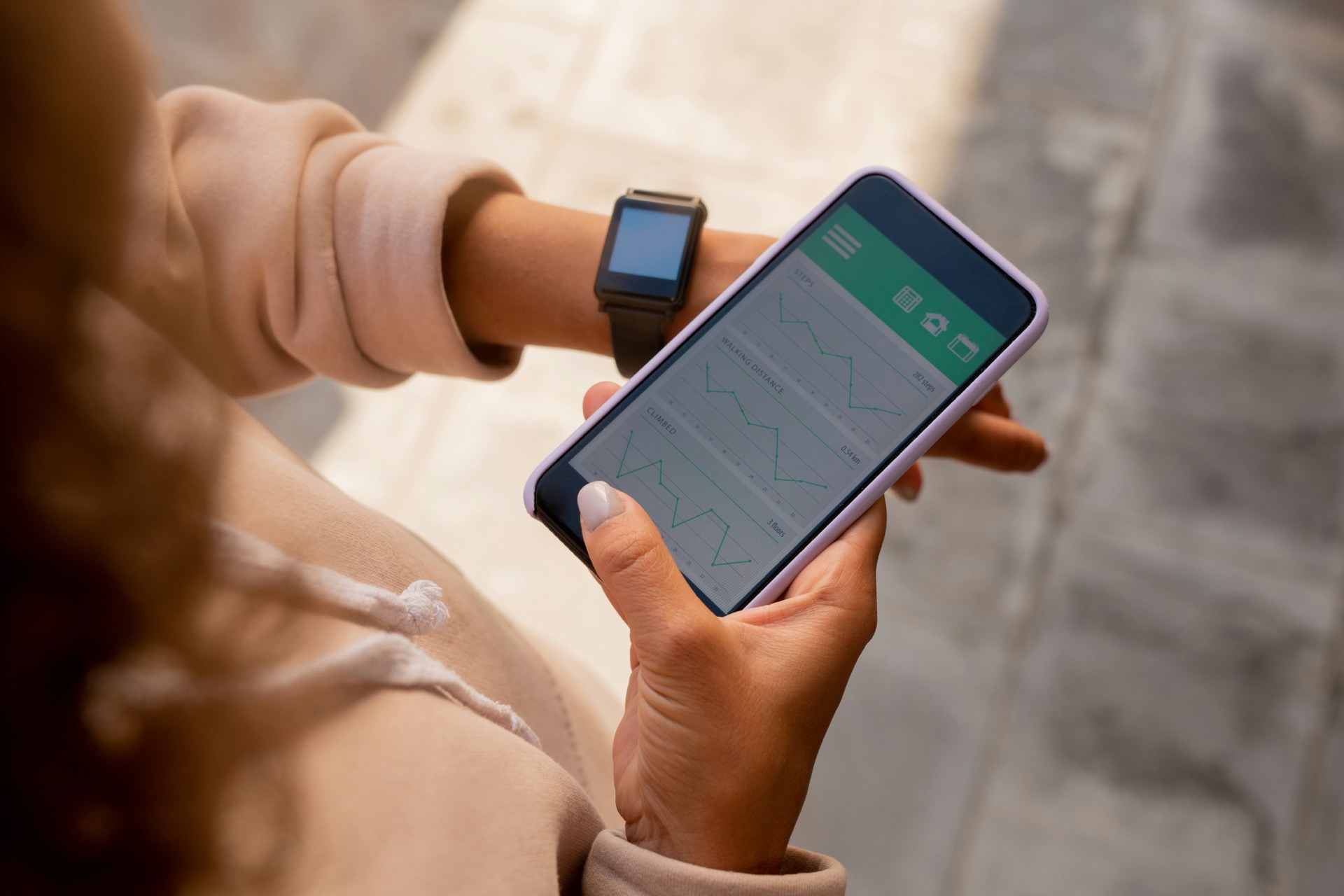 person wearing a smartwatch and checking activity charts on a phone