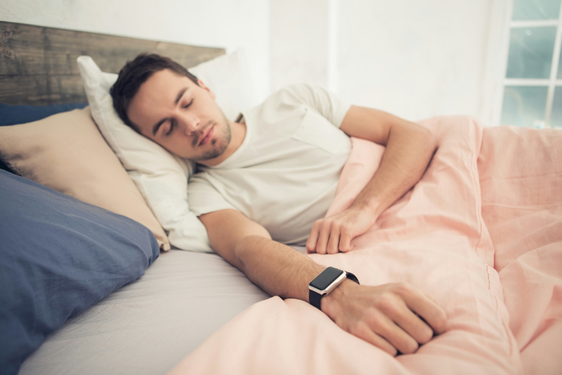 Person sleeping while wearing a smartwatch for sleep tracking.