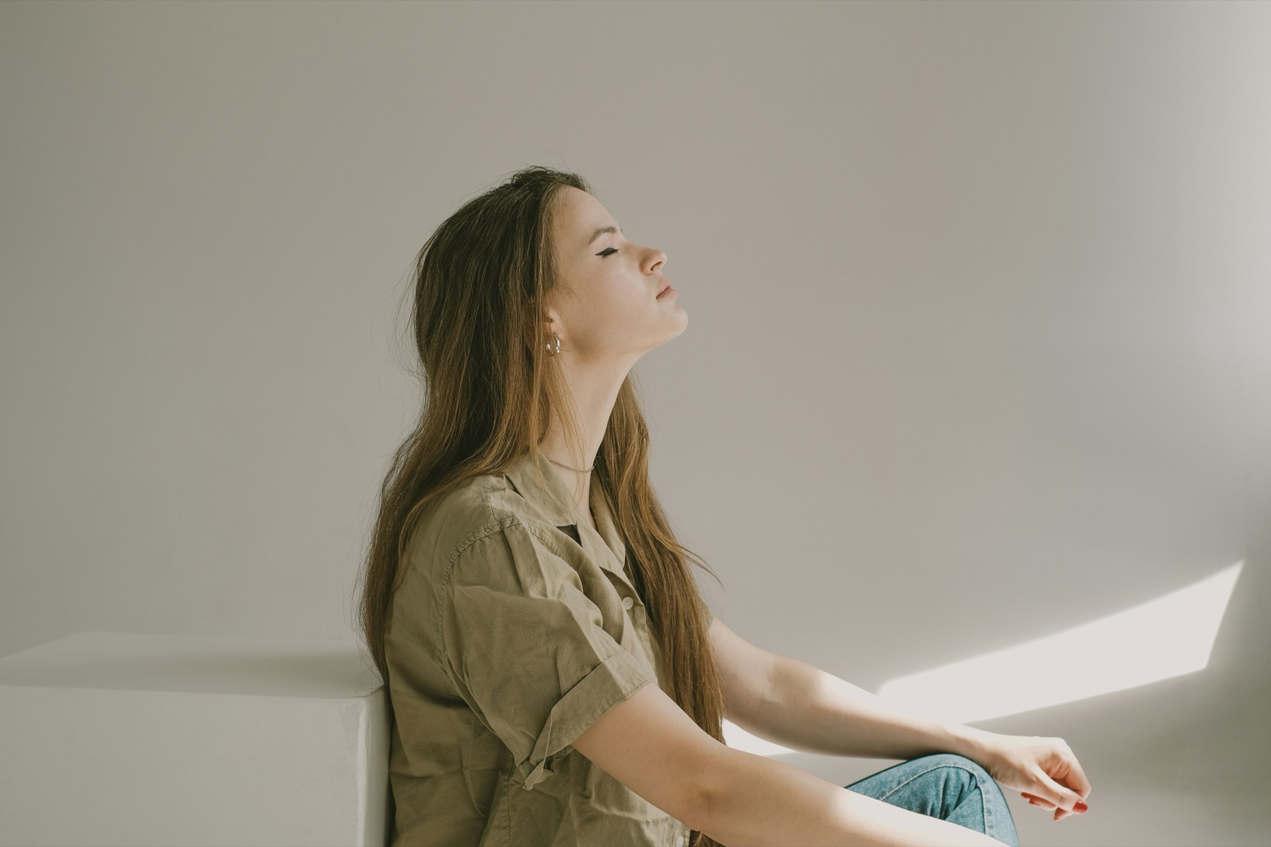 woman sitting with eyes closed and hands resting on her knees before a breathing exercise