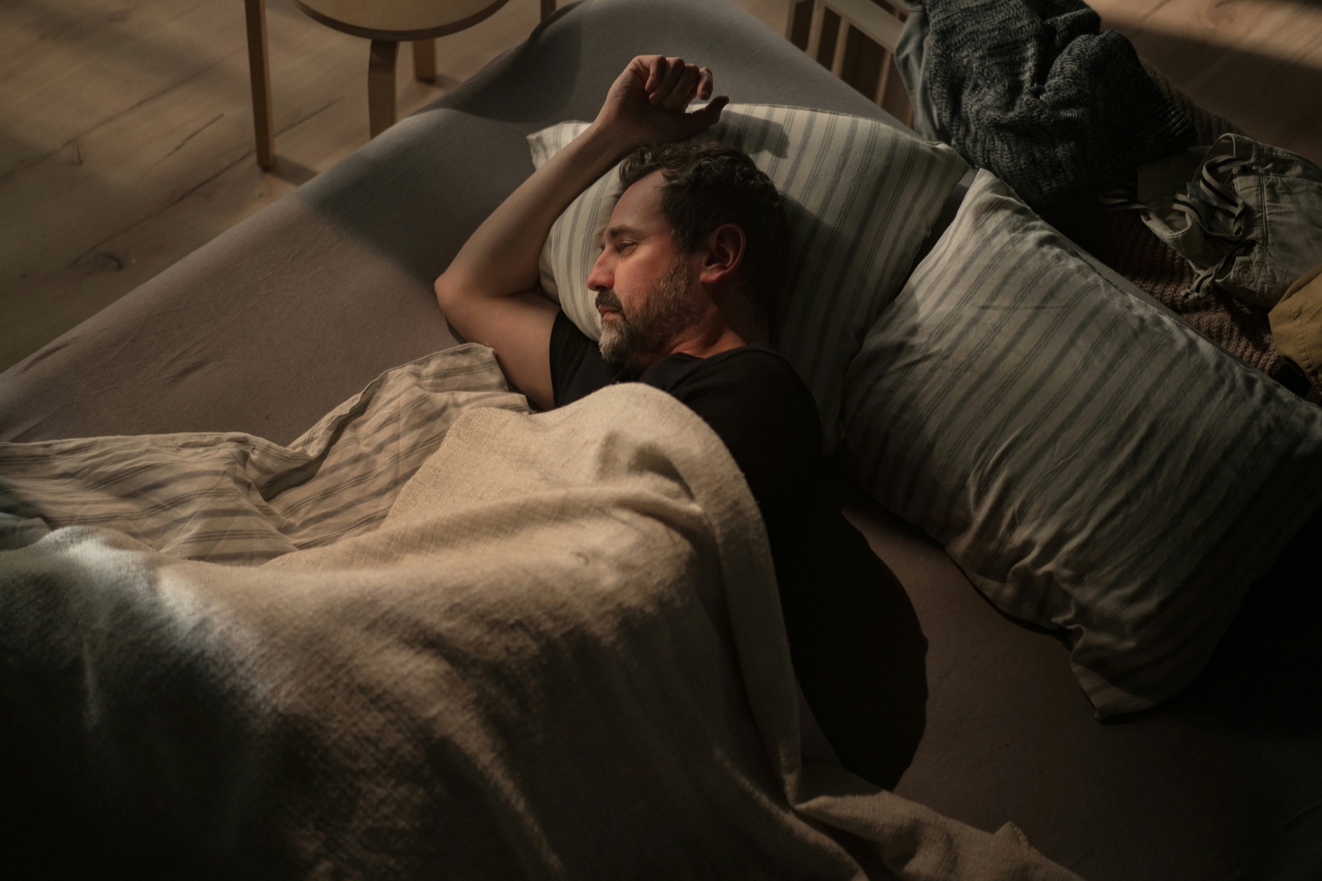 A man resting under a blanket with his head on a striped pillow, illustrating sleep continuity
