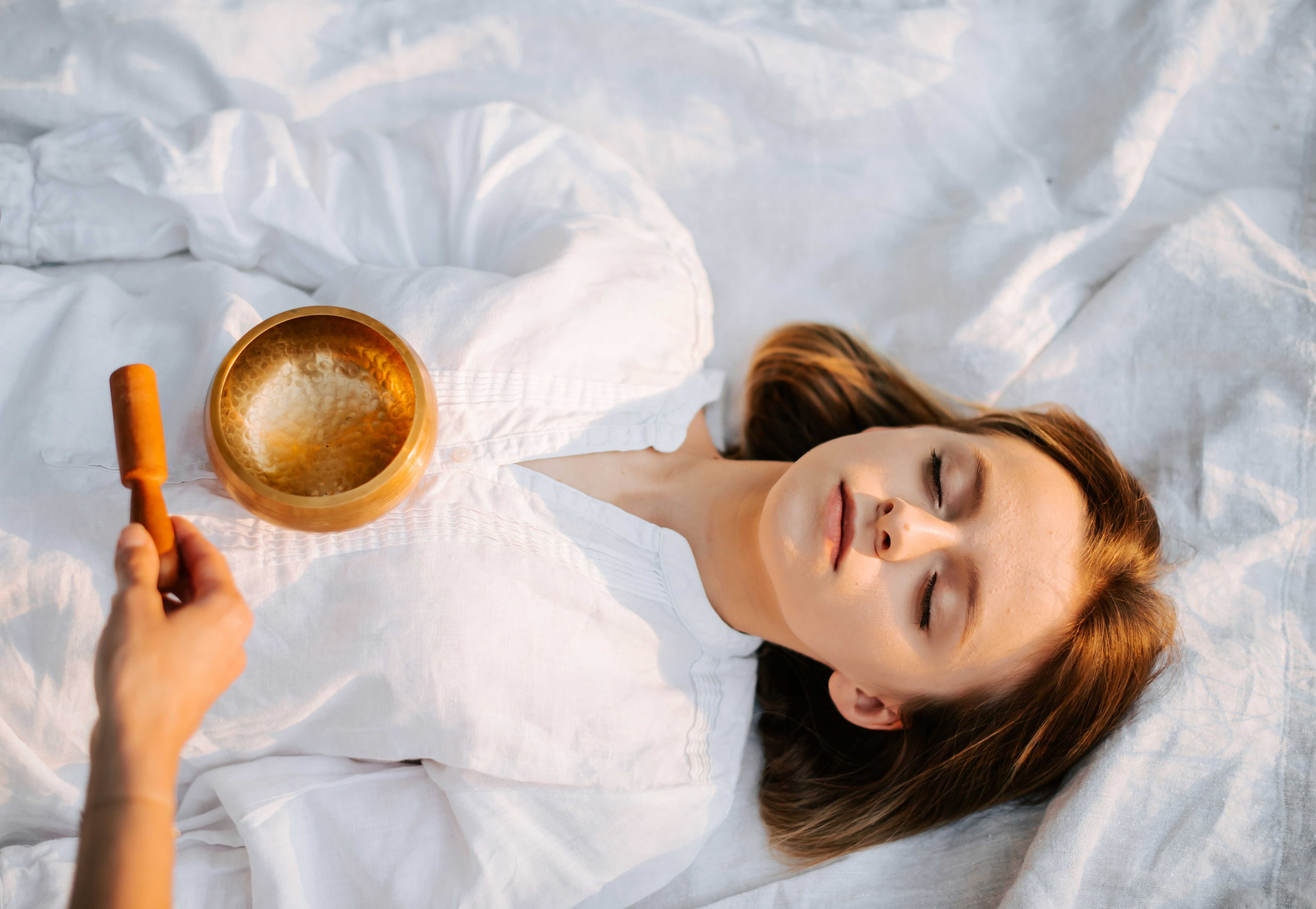 A person resting beside a singing bowl, illustrating a calming practice before sleep