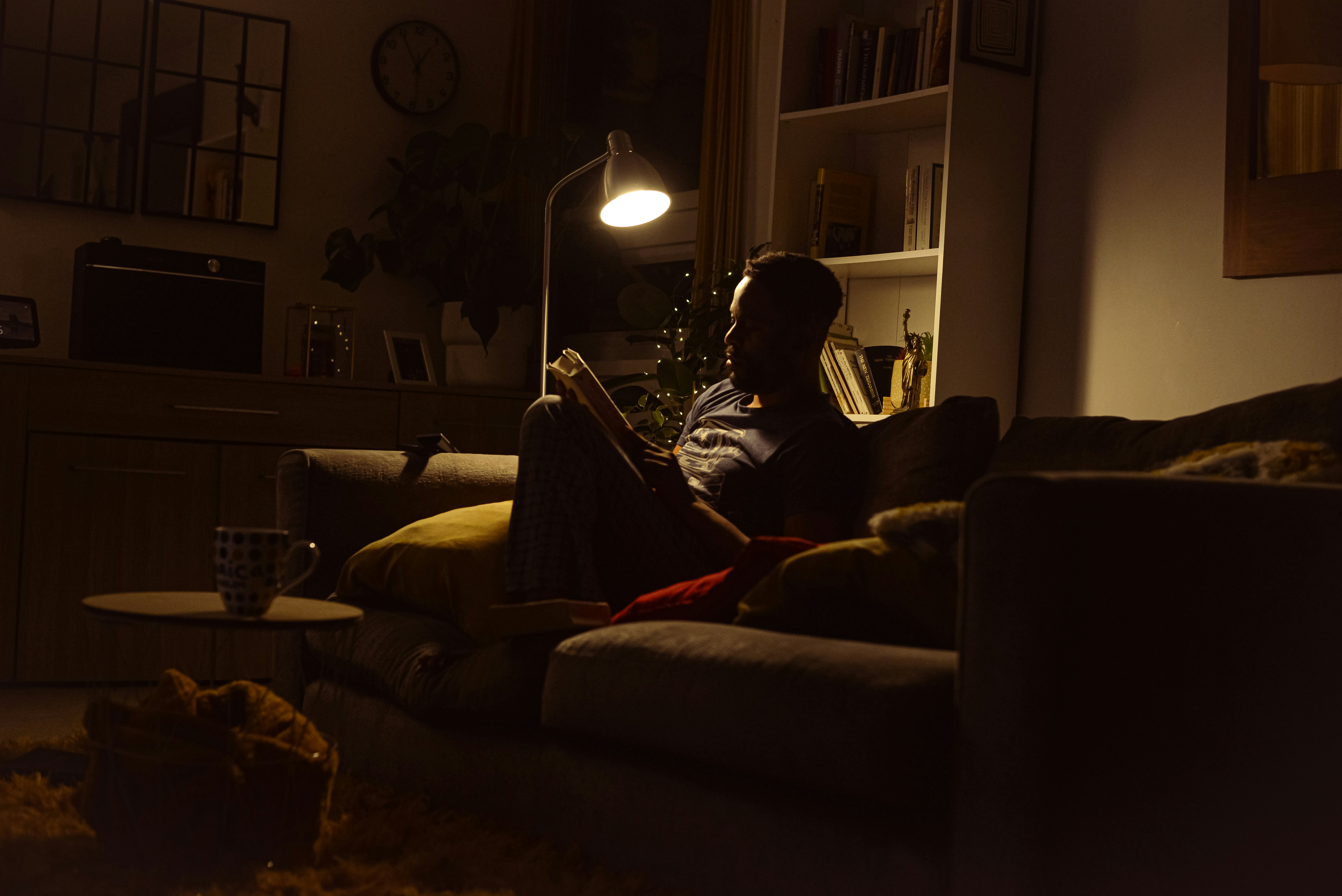 A man reading on a sofa under a warm lamp, illustrating a quiet wind-down before sleep